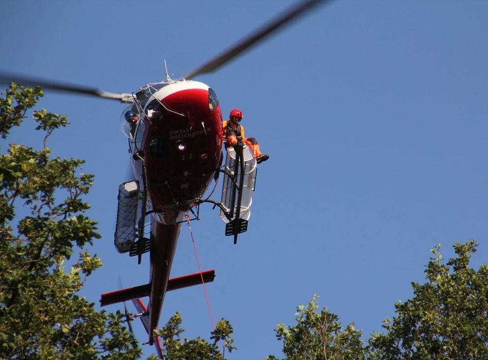 Ein Helikopter fliegt ein paar Meter über den Baumwipfeln.