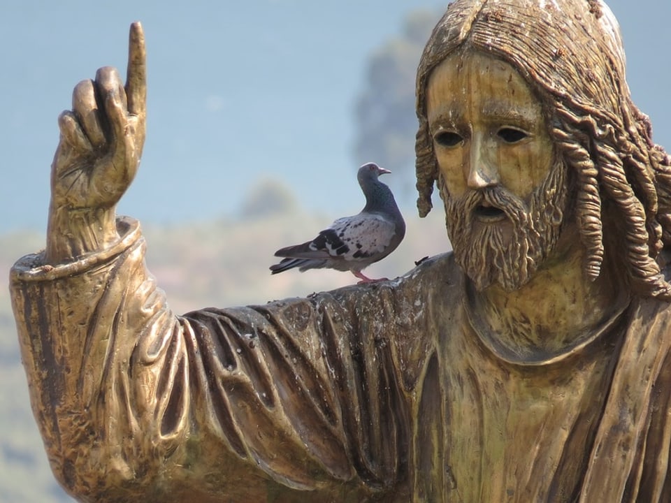 Eine Statue mit mahnendem Finger zu einer Taube.