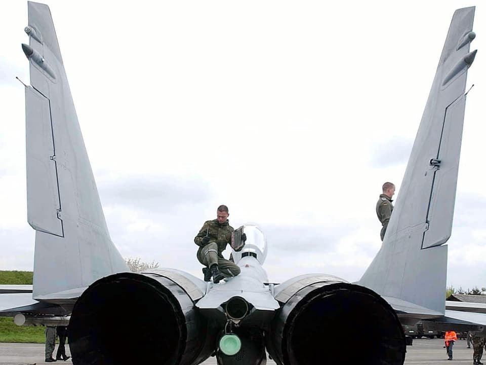 Zwei Mänenr auf einem Militärflugzeug.