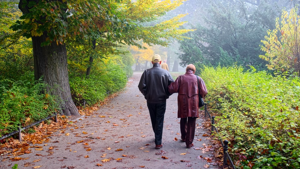 Ein älteres Paar spaziert durch einen Park