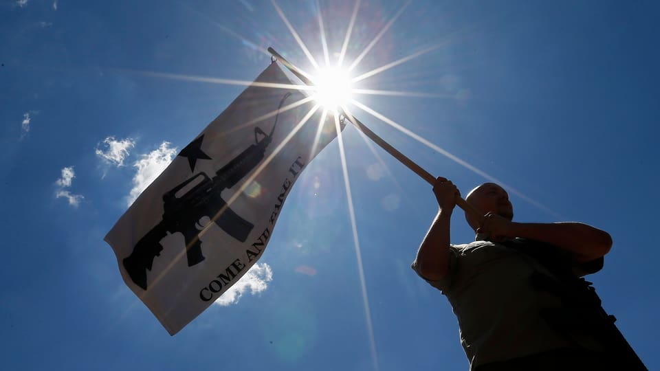 Ein Mann schwenkt eine Fahne mit einem Gewehr.