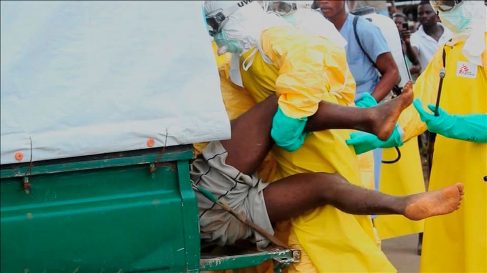 Männer in Schutzanzügen verfrachten einen Ebola-Kranken in eine Ambulanz