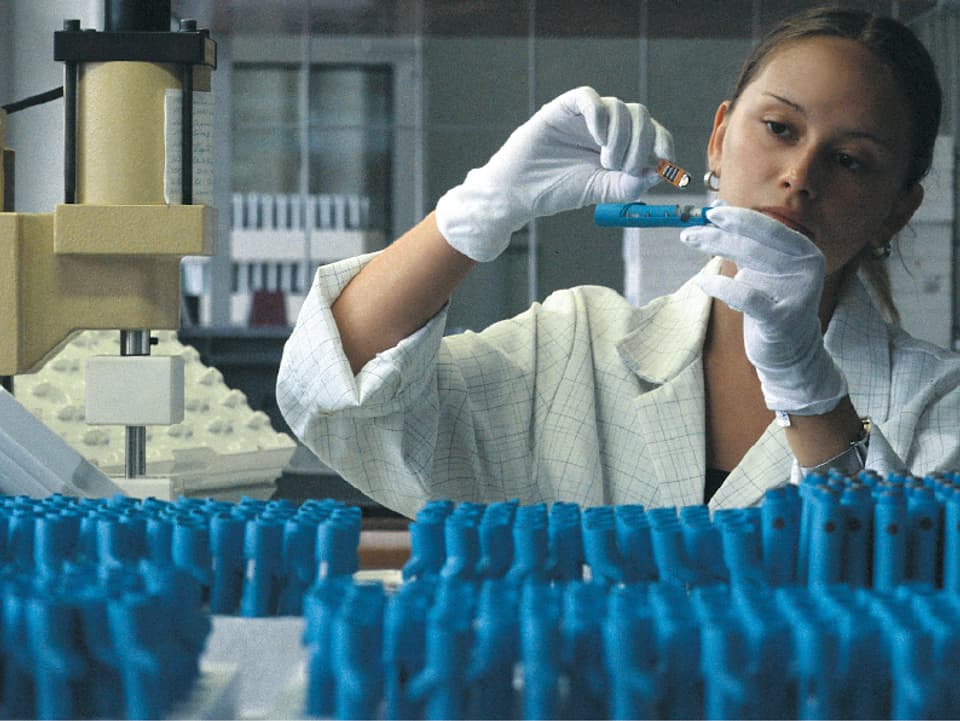 Eine Laborantin beschäftigt sich konzentriert mit der Substanz in einem Reagenzglas.