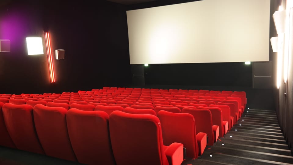 Ein Kinosaal mit roten Sesseln und Leinwand