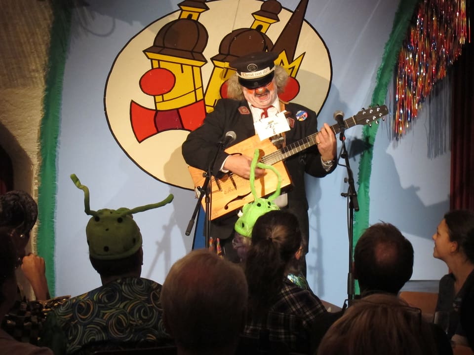 Mann mit roter Nase und Gitarre auf der Bühne