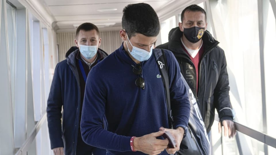 Drei Männer mit Masken laufen einen Gang entlang. 