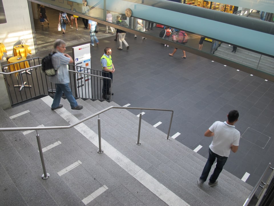 Mann in gelber Weste steht unten an der Bahnhof-Treppe. 