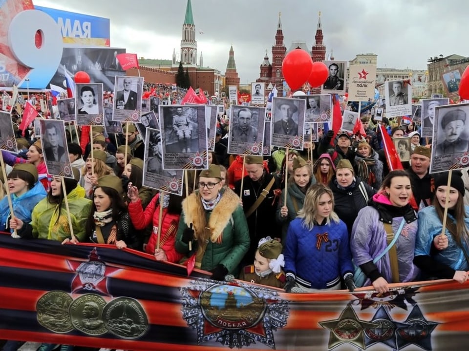 Menschen marschieren mit Bildern ihrer Angehörigen durch Moskau.