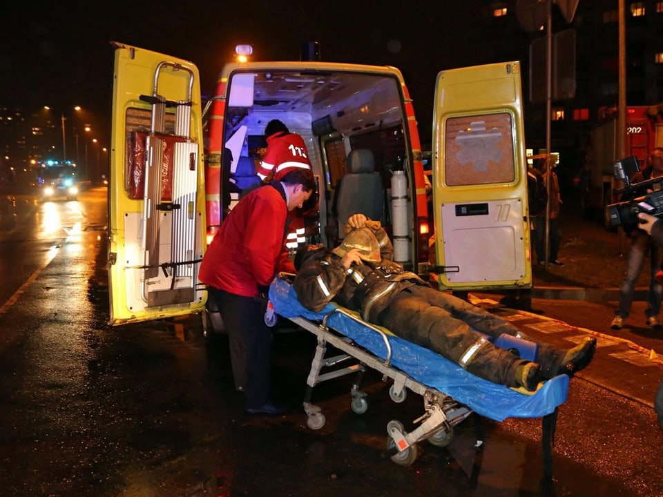 Ein verletzter Feuerwehrmann wîrd in die Ambulanz geschoben.