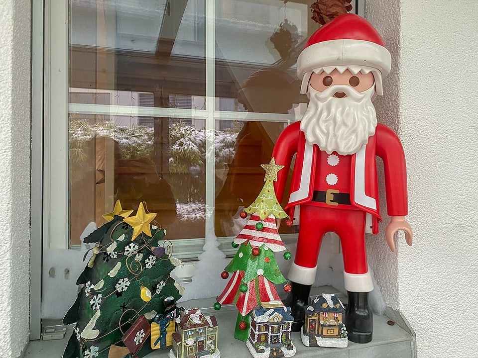 Auf einem Fenstersims steht ein etwa halber Meter grosser Weihnachtsmann, der an eine Playmobil-Figur erinnert.