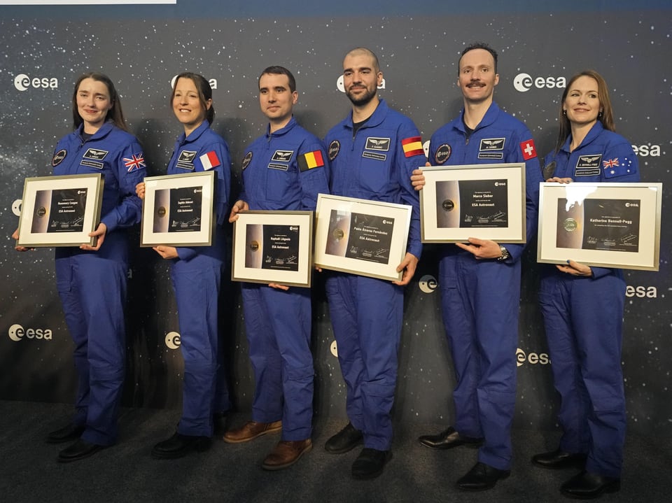 Die neuen Mitglieder des Astronautencorps stehen in einer Reihe und präsentieren ihre Diplome.