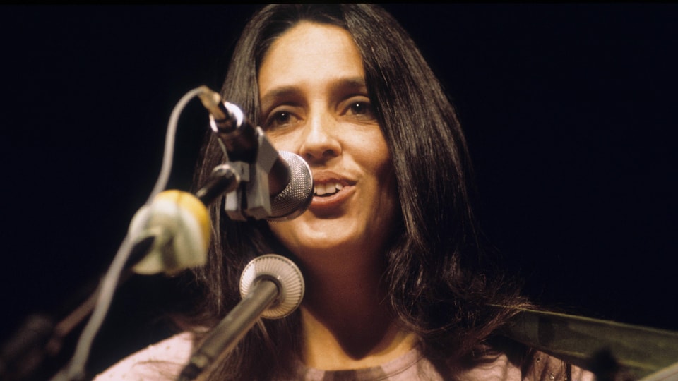 Junge Frau mit langen braunen Haaren singt in Mikrofon