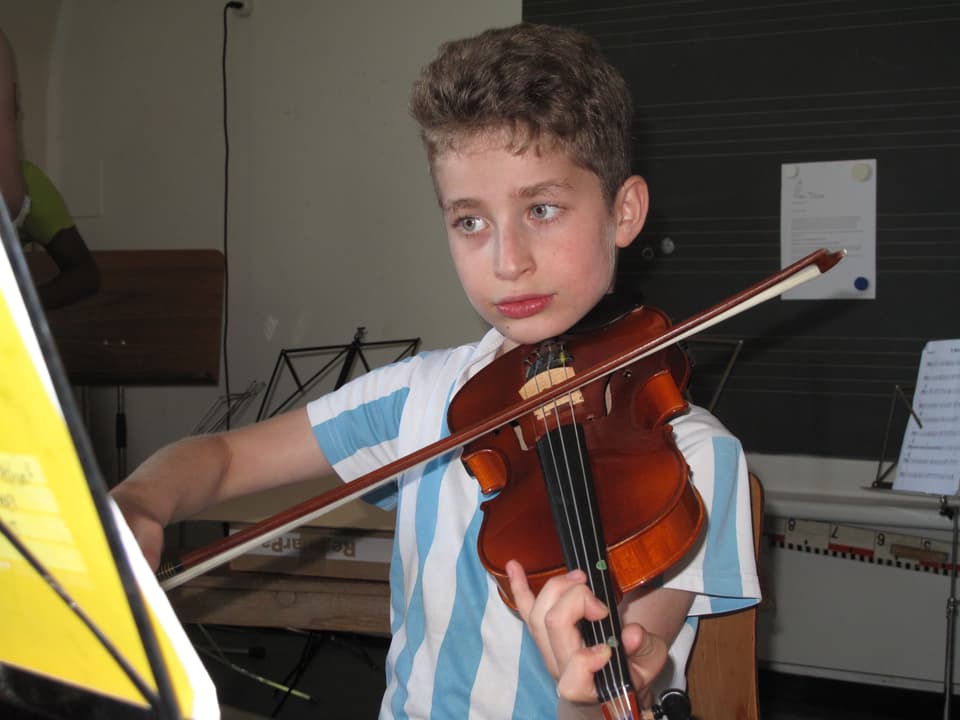 Ein junger Cellist schaut konzentriert auf sein Notenblatt.