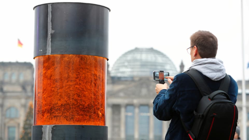 Ein Mann macht ein Handyfoto des temporären Mahnmals vor dem Reichstagsgebäude.