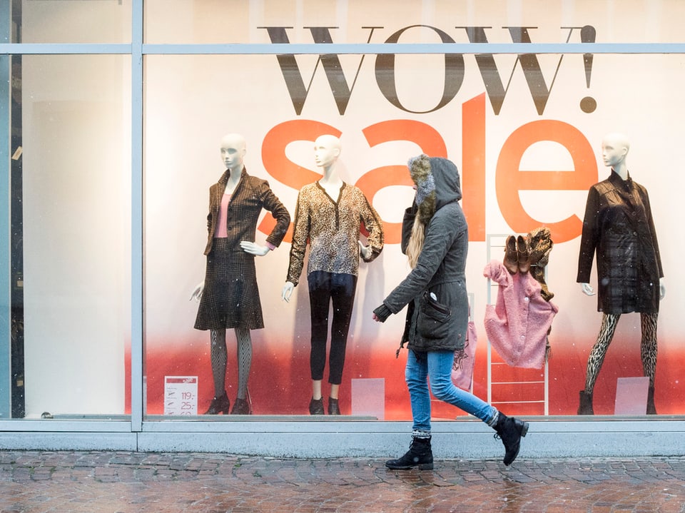 Eine Frau geht an einem Schaufenster vorbei. Dort steht in grossen Buchstaben «Wow! Sale!». (keystone9