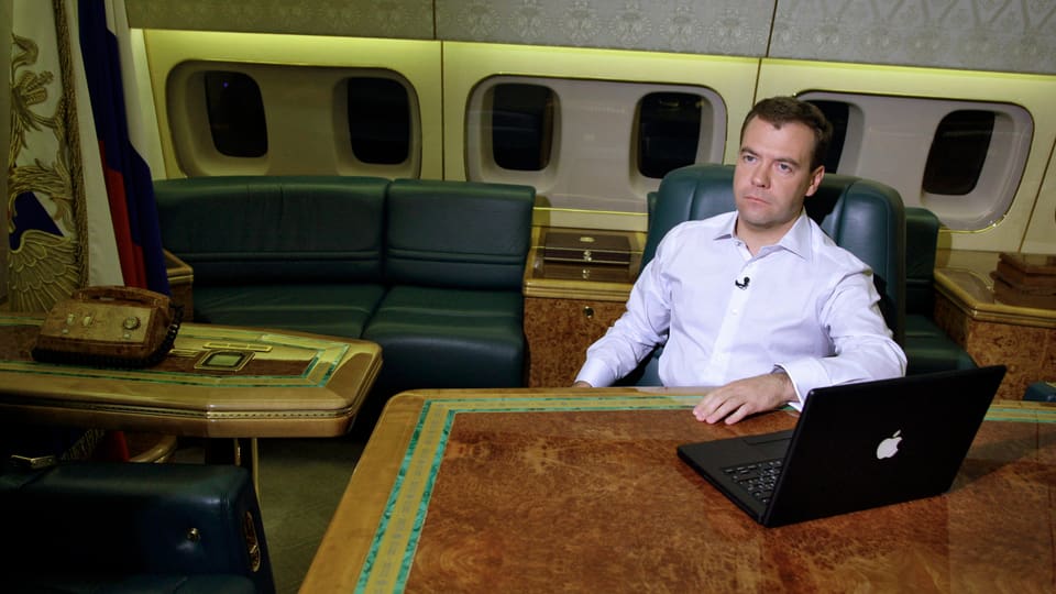 Medwedew in einem Flugzeug vor einem Computer sitzend.