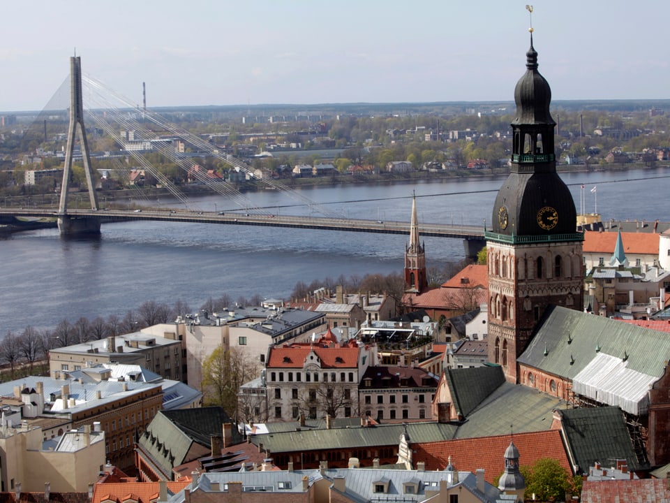 Ansicht der Altstadt am Fluss mit einer modernen Hängebrücke.