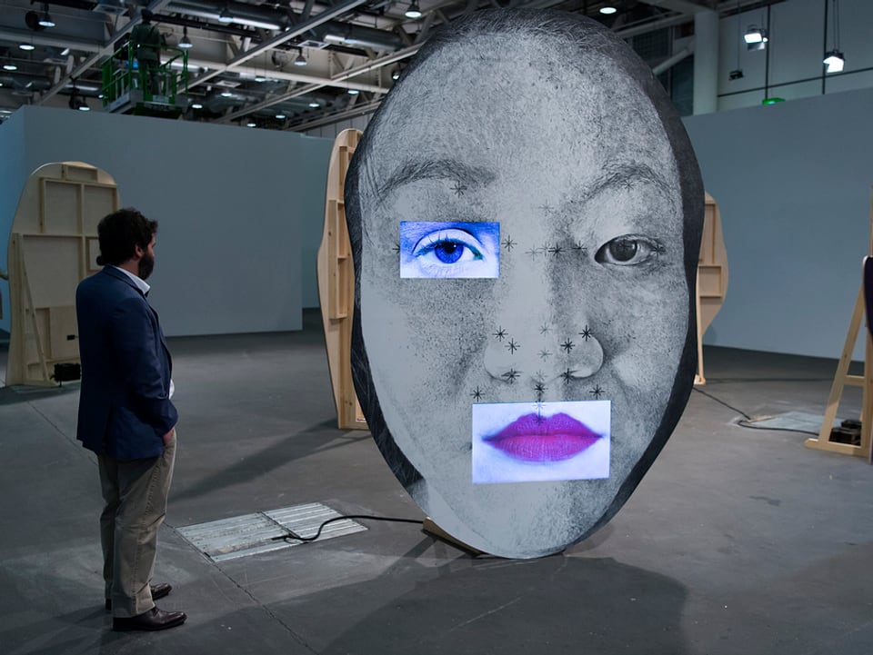Ein Besucher blickt auf ein überdimensionales Gesicht.