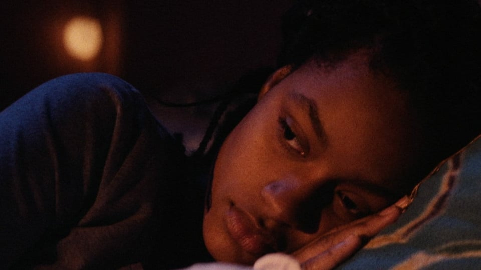 Eine junge schwarze Frau liegt im Bett.