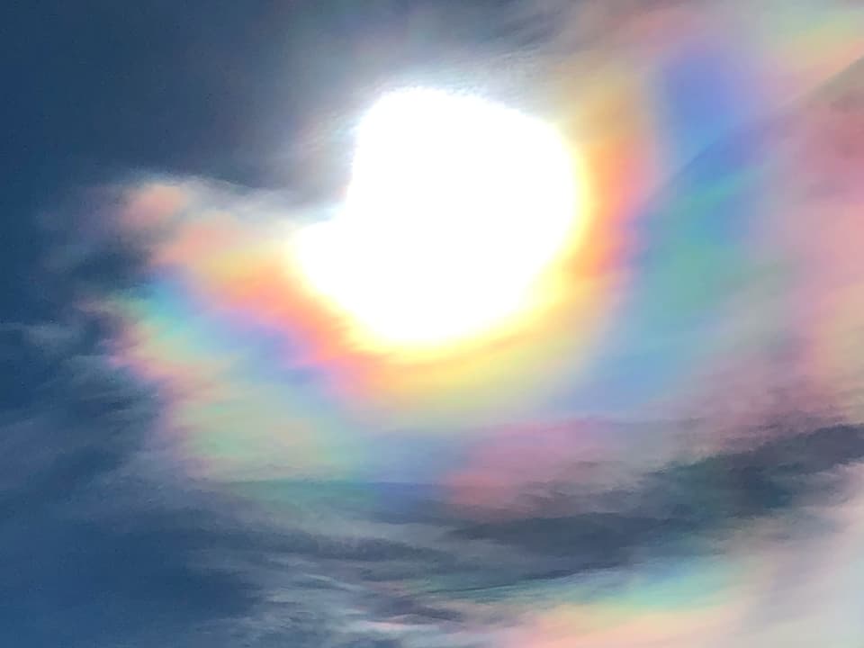 Irisierende Wolken schimmern in Perlmutfarben.