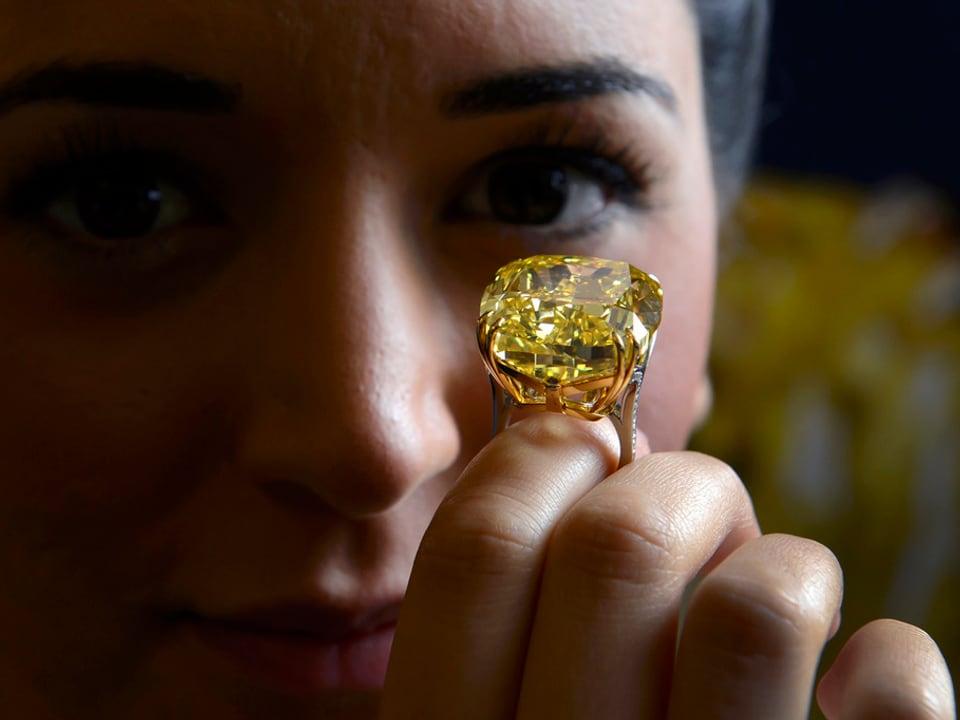Eine Frau mit einem gelben Diamanten am Finger. 