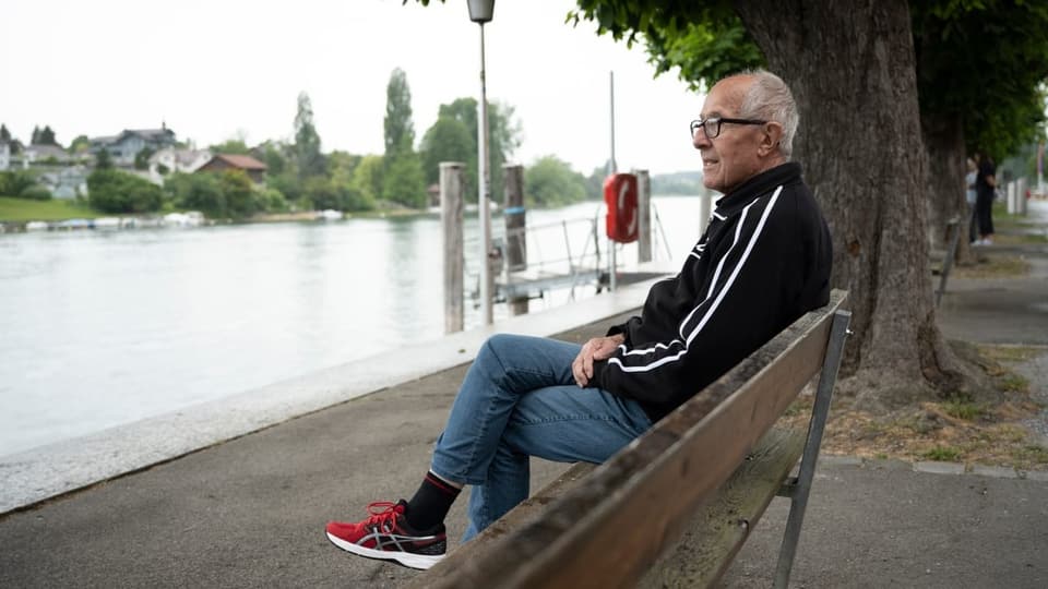 ein älterer Mann auf einer Bank am Fluss