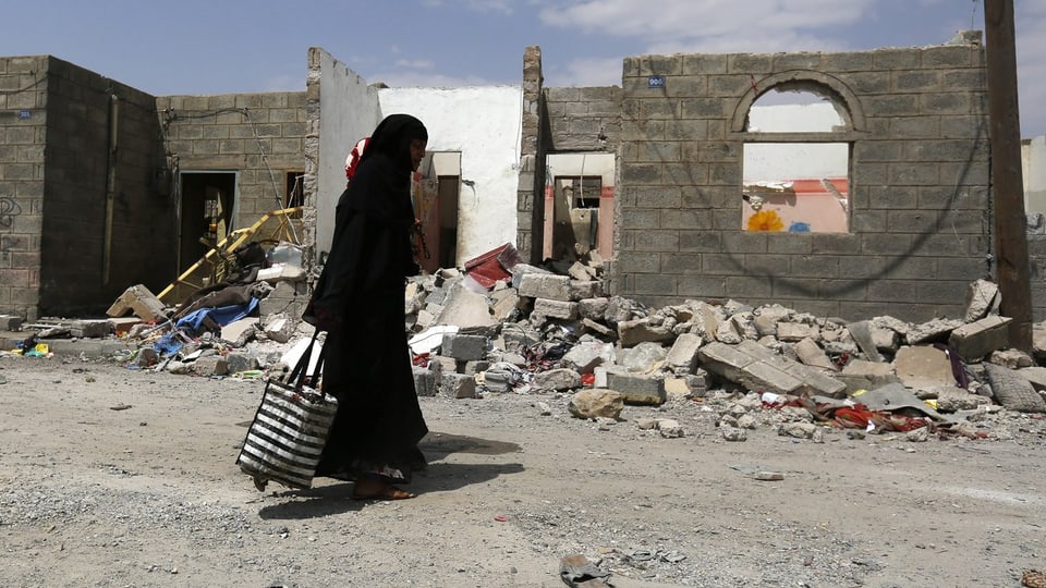 Frau geht durch Ruinen in Jemens Hauptstadt Sanaa. 