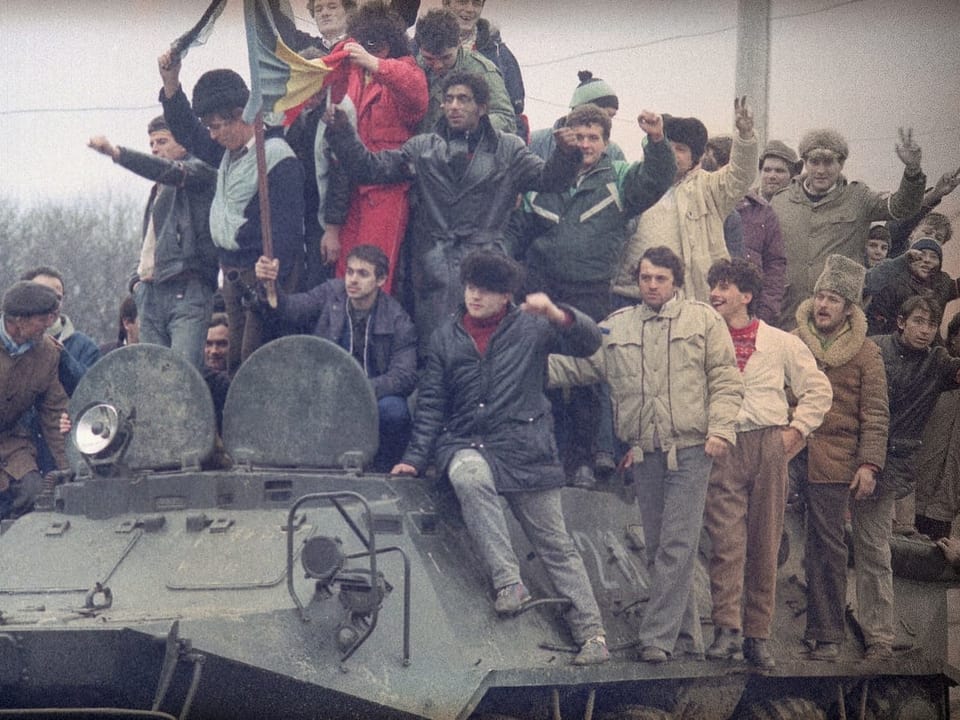 Zivilisten stehen dicht gedrängt auf einem Panzerfahrzeug