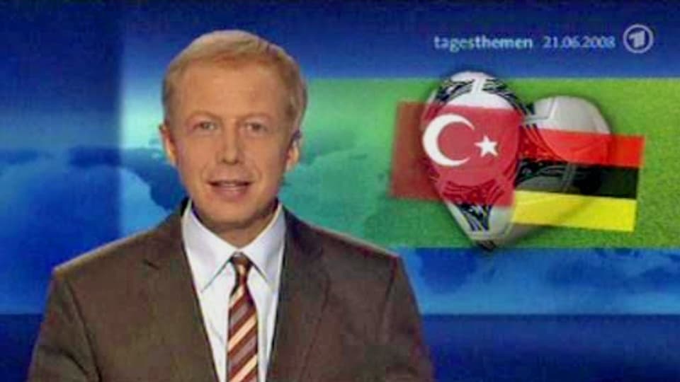 Ein Moderator preist ein Fussballspiel an – im Hintergrund ist die falsche Deutschlandflagge eingeblendet. 