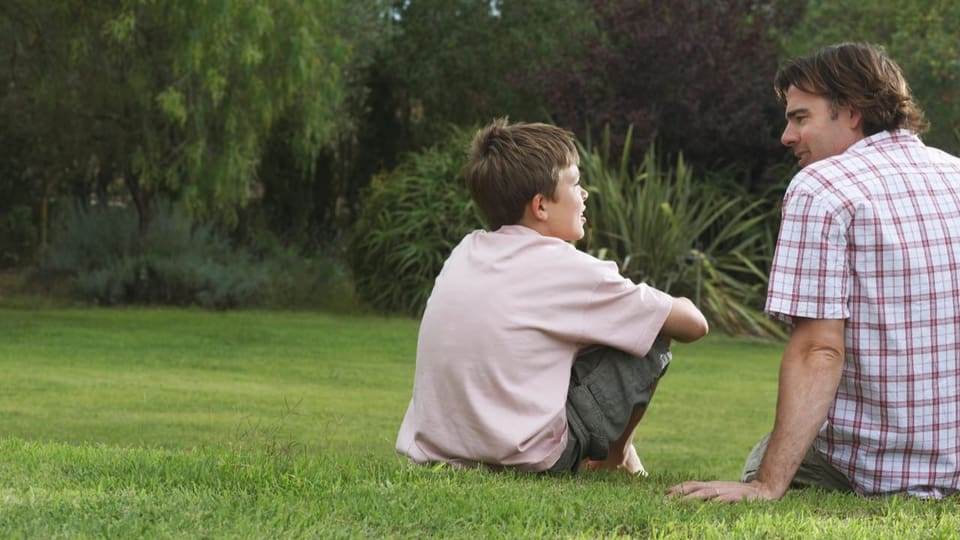 Ein Junge und sein Vater auf dem Rasen.