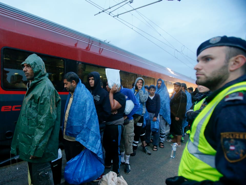 Flüchtlinge vor stehendem Zug. 