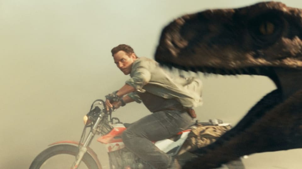 Ein Mann fährt auf einem Motorrad, im Vordergrund der Kopf eines Dinosauriers