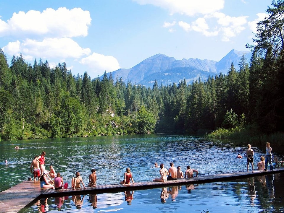 Am Crestasee in Graubünden sitzen Leute auf dem Steg.