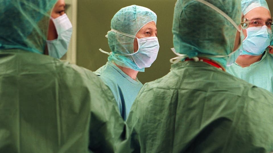 Vier Ärzte in OP-Kittel und Mundschutz in einem Schweizer Spital (Archivbild).