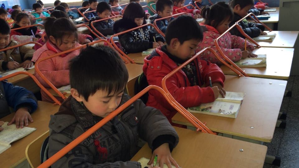 Eine chinesche Schulklasse beim Schreiben mit Metallbügeln als Distanzhalter.