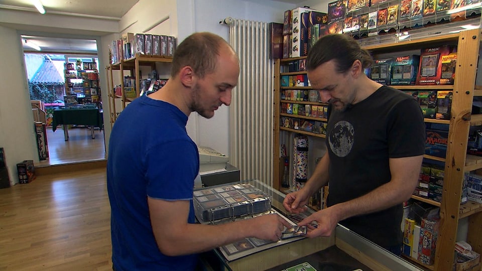 Zwei Männer an Ladentheke über Karten gebeugt