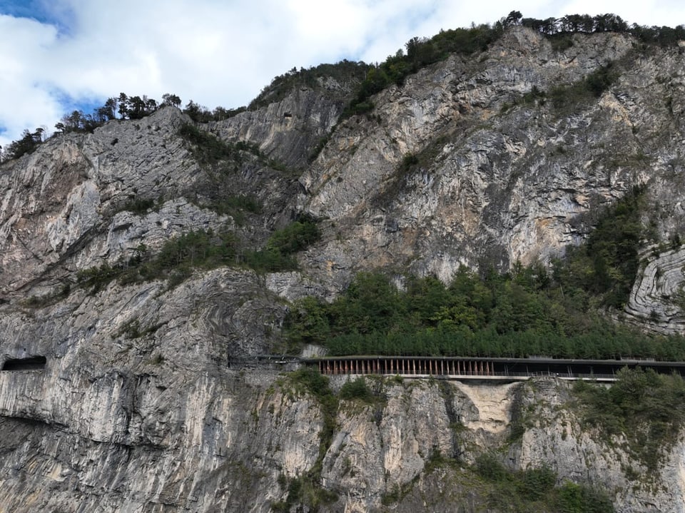 Paisagem montanhosa com árvores e pequeno túnel ferroviário.
