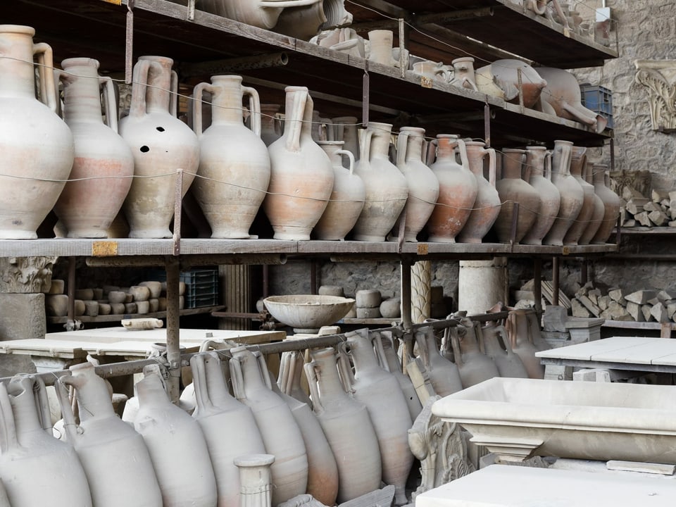 Viele antike Vasen stehen in einem Regal.