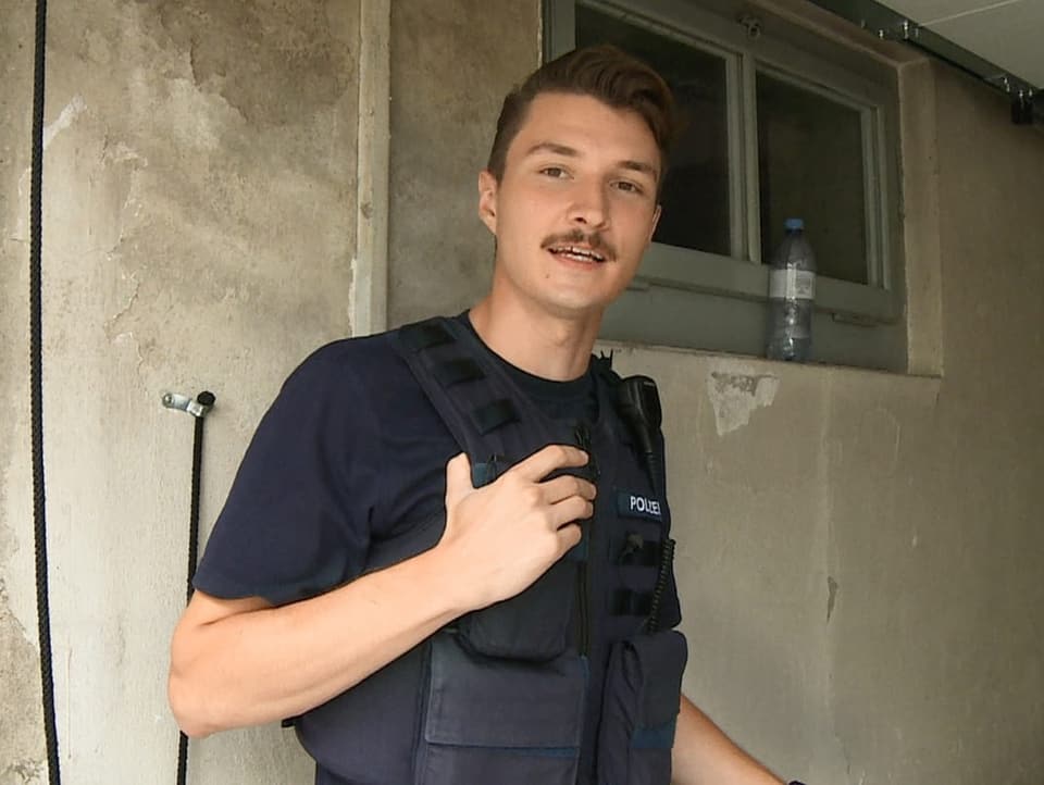 Junger Mann mit Schnauz in einer Polizeiuniform.