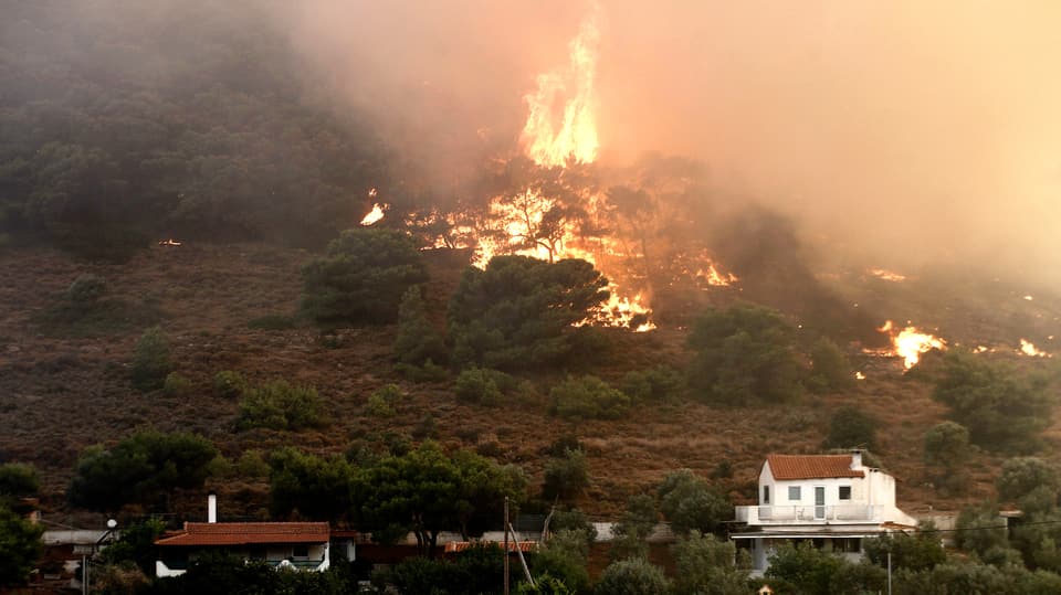  Athener Stadtteils Kareas. Mächtige Flammen stechen aus einem Waldstück in der Nähe von Wohnhäusern im Athener Stadtteil Kareas.