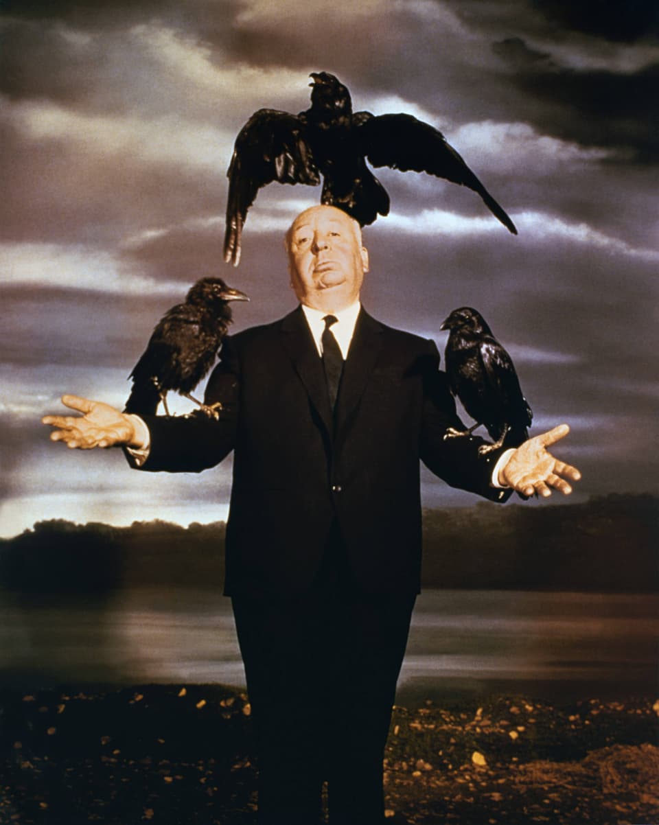 Promo-Foto des Films «Die Vögel»: Regisseur Alfred Hitchcock posiert als Vogelscheuche mit drei Krähen auf Kopf und Armen.