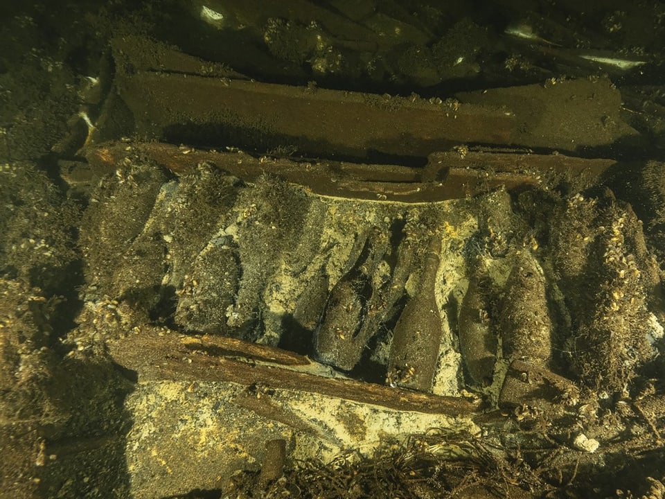Underwater shot of bottles covered in debris.