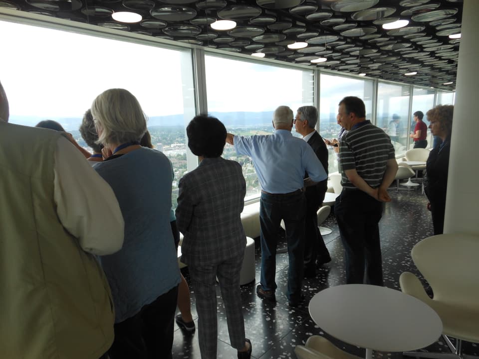 Eine Gruppe Besucher blicken aus dem 38. Stockwerk des Roche-Turms auf Basel hinunter.