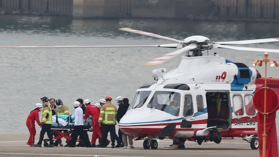 Lee Jae Myung wird auf einer Barre zu einem Helikopter geschoben.