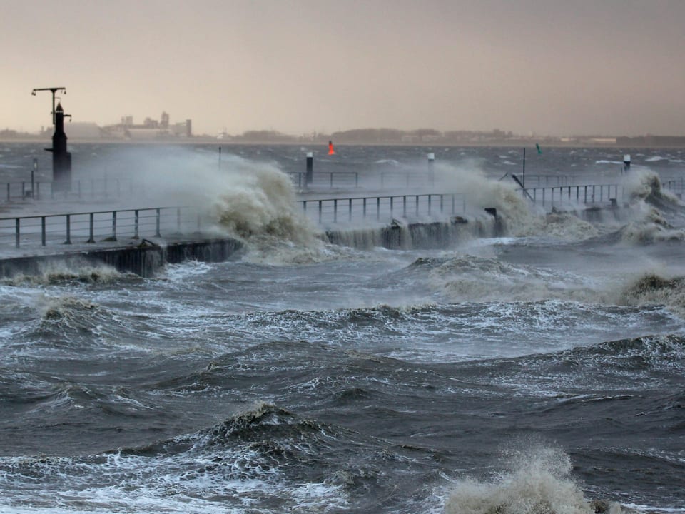 In der Nähe der Stadt Emden peitscht der Sturm die Nordsee gegen eine Brücke. 