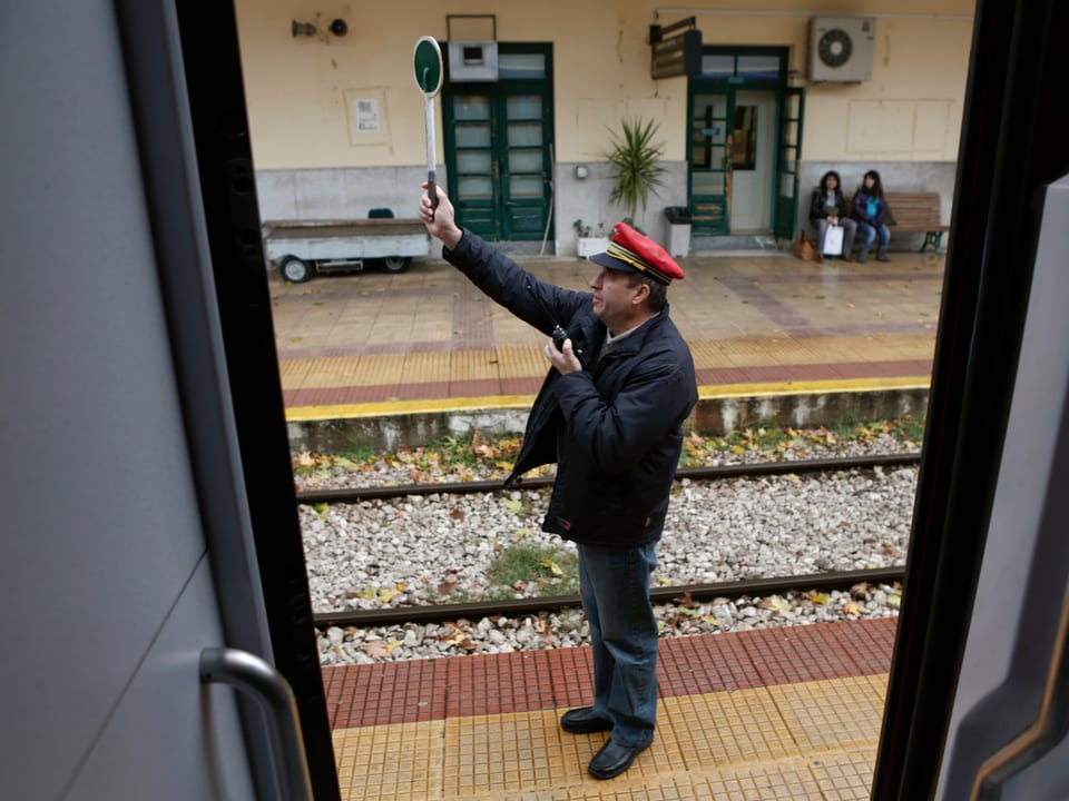 Ein Zugbegleiter hält eine grüne Tafel in die Luft