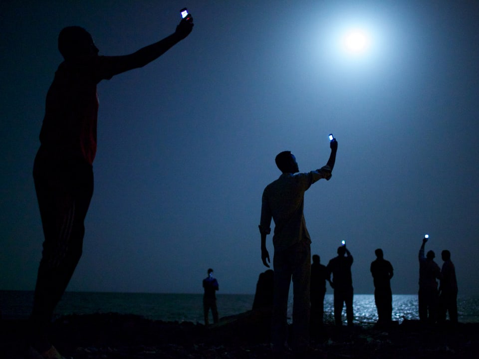 Menschen halten nachts ihr Handy in die Luft.