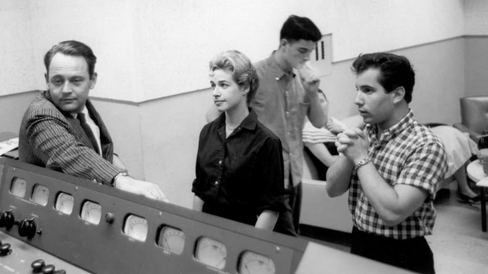Carole King, Paul Simon (rechts) und Gerry Goffin (hinten) stehen in einem Aufnahme-Studio.