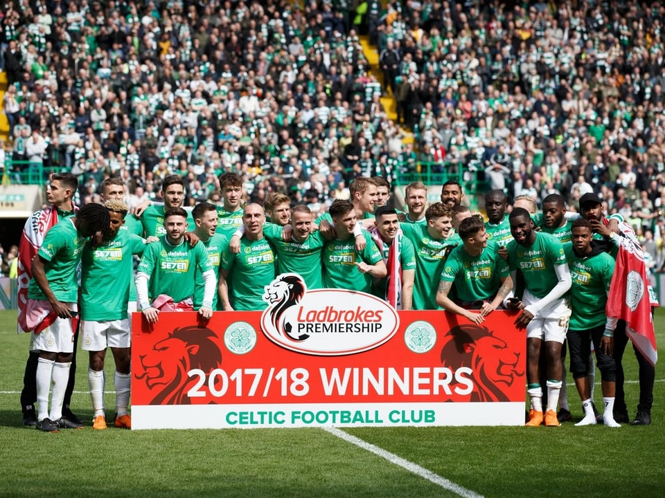 Die Spieler von Celtic bejubeln die Meisterschaft hinter dem Sieger-Plakat.