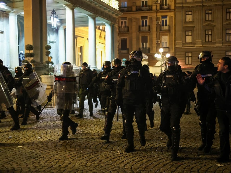 Einsatzkräfte der Polizei gehen in Vollmontur vor dem Belgrader Rathaus vorbei.